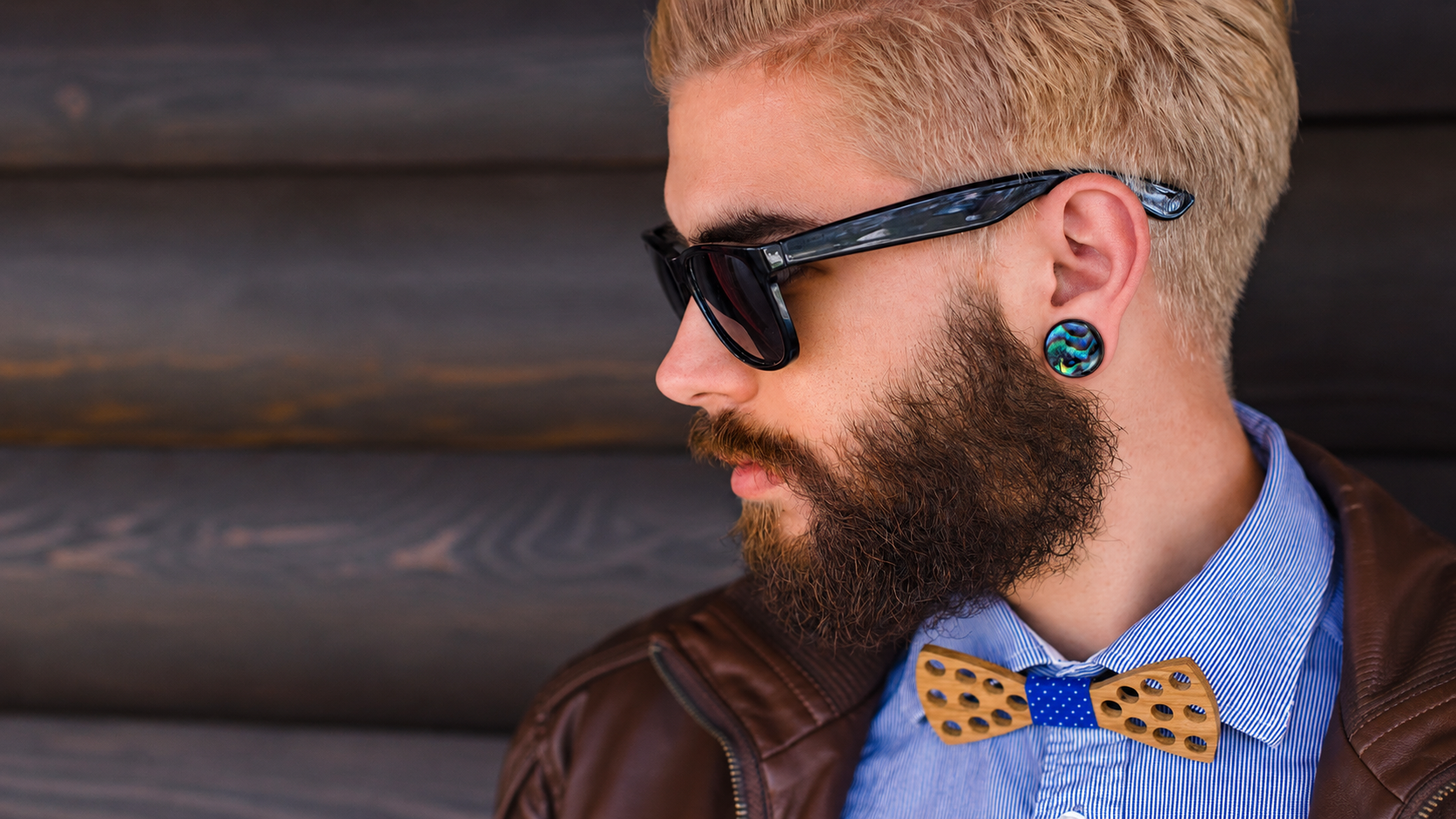 Portrait urbain d’un homme barbu portant plug d'oreille en bois serti de nacre abalone